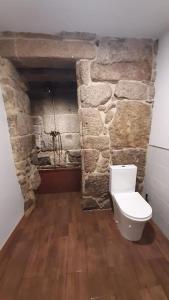 a bathroom with a toilet in a stone wall at Casas da Bríxida. Apartamento accesibel in Cangas de Morrazo
