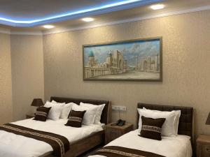 Archie Family Hotel في طشقند: غرفة فندقية بسريرين ولوحة على الحائط