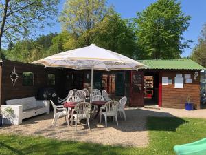 uma mesa e cadeiras debaixo de um guarda-sol num quintal em Ferienpark Eifellux em Körperich