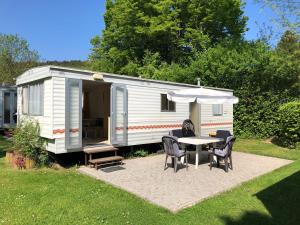 ein weißer Wohnwagen mit einem Tisch, Stühlen und einem Sonnenschirm in der Unterkunft Ferienpark Eifellux in Körperich