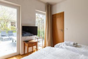 Un dormitorio con una cama y un televisor y un balcón. en Strandleben - Galerie Nummer 13, en Ahrenshoop 33 fotos más