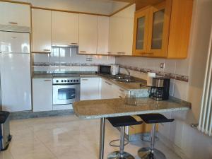 kuchnia z białymi urządzeniami i blatem ze stołkami w obiekcie APARTEMENTOS PASEO DE LORDELO - 2 Derecha w mieście O Grove