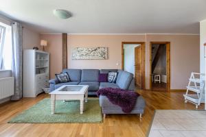 a living room with a blue couch and a table at Denkerhof Ferienwohnung Deichblick in Reußenköge