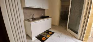 eine Küche mit weißen Schränken und einer Spüle sowie Fliesenboden in der Unterkunft Zì Gì B&B in Porto Cesareo