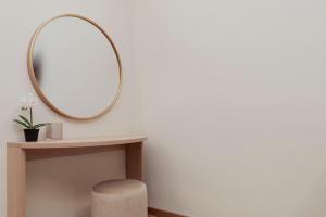 a round mirror on a wall next to a table with a stool at Cesare ai Cavalieri Suites in Rome