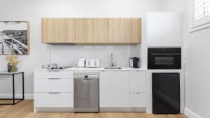 a kitchen with white cabinets and a dishwasher at Easy Stroll - Ettalong Beach in Ettalong Beach
