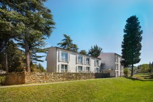 a house on a hill with a stone wall at Villas - Hotel & Resort Adria Ankaran in Ankaran