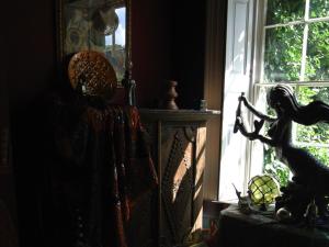 a statue of a mermaid standing in front of a window at The Covenstead in Glastonbury