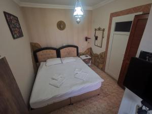 een kleine slaapkamer met een bed met witte lakens bij Anz Guest House Pansiyon in Selcuk