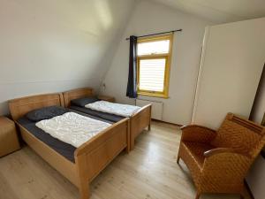 1 dormitorio con 2 camas, ventana y silla en Albatros 6 personen en Julianadorp