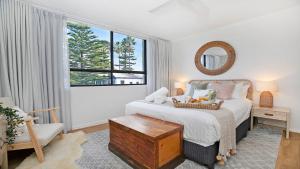 a bedroom with a bed and a large window at St Tropez Beachside Luxe in Kiama
