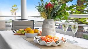 a table with a vase of flowers and a plate of food at St Tropez Beachside Luxe in Kiama
