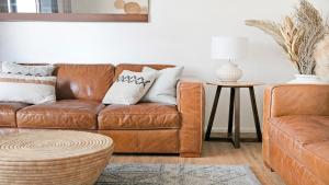 a living room with a brown leather couch and a table at St Tropez Beachside Luxe in Kiama +18 photos