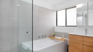 a white bathroom with a tub and a sink at St Tropez Beachside Luxe in Kiama