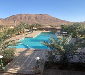 een zwembad met palmbomen en een berg op de achtergrond bij La Perle Du Drâa in Zagora