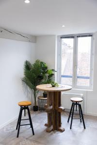 a table and two stools in a room with a window at Doux Cocon Tropical au cœur du centre ville in Troyes