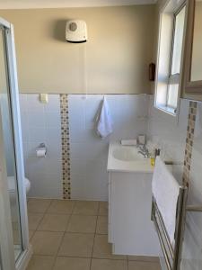 een witte badkamer met een douche en een wastafel bij Amazing Aubrey, walk to Bremner Bay in Wanaka