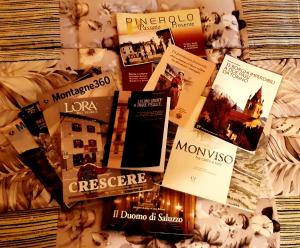 a bunch of books sitting on top of a bed at La Marmotta in Luserna San Giovanni