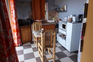 La cuisine est équipée d'une table, de chaises et d'un réfrigérateur blanc. dans l'établissement La Rond'Dada, à Sainte-Suzanne