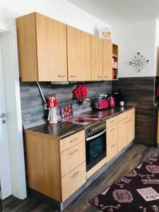 uma cozinha com armários de madeira e um forno com placa de fogão em Ferienwohnung Seenrunde 