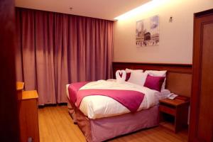 a bedroom with a large bed with pink and white sheets at Al Bostan Al Masi Hotel in Makkah