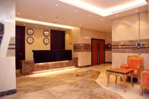 a living room with a tv and a table and clocks at Al Bostan Al Masi Hotel in Mecca