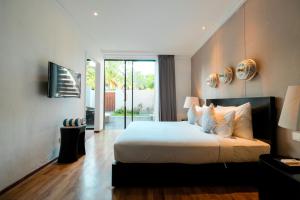 Un dormitorio con una cama grande con sábanas y almohadas blancas. en The Lavana Akatara Villa Nusa Dua, en Nusa Dua 20 fotos más