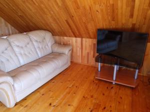 a living room with a white couch and a flat screen tv at Guest house Vilciņi in Bernāti