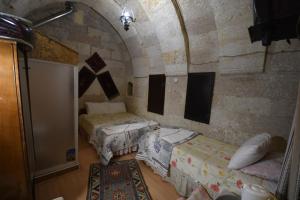 a room with two beds in a stone wall at Dar Konak Pansiyon in Ürgüp