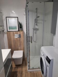 a bathroom with a shower and a toilet and a washing machine at Apartament Nowowiejskiego in Świnoujście