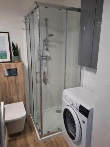 a bathroom with a shower and a washing machine at Apartament Nowowiejskiego in Świnoujście