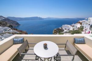 einen Tisch und Stühle auf einem Balkon mit Meerblick in der Unterkunft Elegant Santorini Villa Villa Spyros Villa Demi Private Hot Tub Air Conditioning 2 Bedroom in Oia