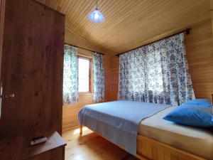 una camera da letto con un letto con cuscini blu e una finestra di Hurmalık Apart Evleri-Very Close to the Sea Large Garden Bungalow with Barbecue and Swing a Karaoz
