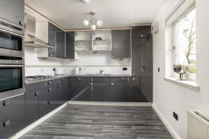 a kitchen with gray cabinets and a window at Executive Apartment, Free Parking, West End in Aberdeen