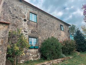 an old stone building with two windows and some bushes at QUINTA DO CAMBEIRO in Viana do Castelo