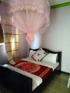 ein Schlafzimmer mit einem Bett mit einem Fenster und einem Vorhang in der Unterkunft Gugga Resort in Soroti