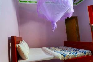 a small bedroom with a bed with a purple ceiling at Gugga Resort in Soroti
