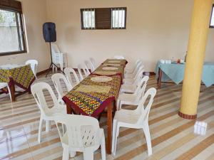 a dining room with a table and white chairs at Gugga Resort in Soroti