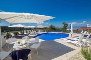 a swimming pool with white chairs and an umbrella at Villa Poseidon Rova by EL-PI TOURS in Malinska