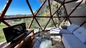 a living room with a tv and a large window at DomoCantabria in Sobremazas