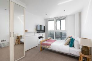 ein weißes Schlafzimmer mit einem Bett und einem TV in der Unterkunft Serene Waterfront Rooms - ExCel in London