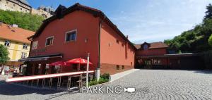 a red building with a red umbrella on a street at Hotel Karlštejn & SPA in Karlštejn