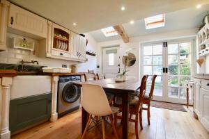 a kitchen with a wooden table and chairs and a laundry room at Cockle Cottage, An artists haven, Charming Cottage By Air Premier in Seaford