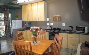 a kitchen with a wooden table with a vase of flowers on it at Big 5 Guest House Witbank in eMalahleni