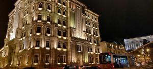 un bâtiment éclairé dans une rue la nuit dans l'établissement Azneft Royal Suite Apartment Sea View, à Baku