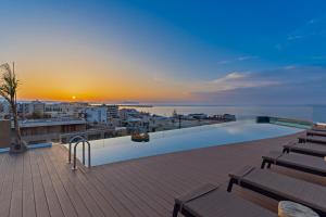 a rooftop deck with a swimming pool and the sunset at Minos Ambassador Suites & Spa - Adults only in Rethymno