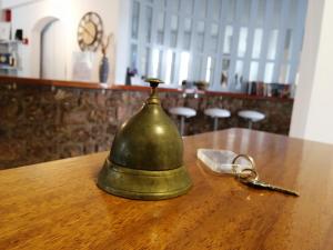 a green bell on a wooden table with a pair of handcuffs at 7 Islands in Spetses