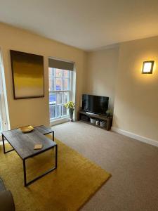 a living room with a table and a tv at Flat 1 Chestergate in Macclesfield