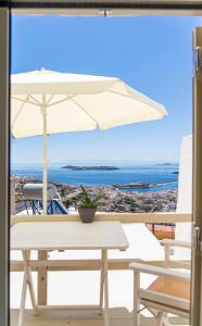 a white table and an umbrella on a balcony at Tarik Home live traditional in Ano Syros