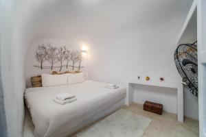 a white bedroom with a white bed with trees on the wall at AURORA VILLA by K&K in Oia +45 photos